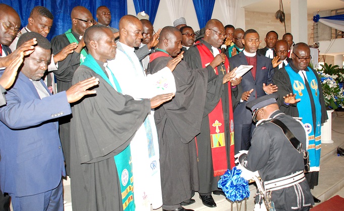 Rt Rev. Seth Senyo Agidi (speaking into the mic), Rev. Lawrence Tetteh  and other members of the clergy praying for the IGP, Mr John Kudalor, at the  induction service yesterday